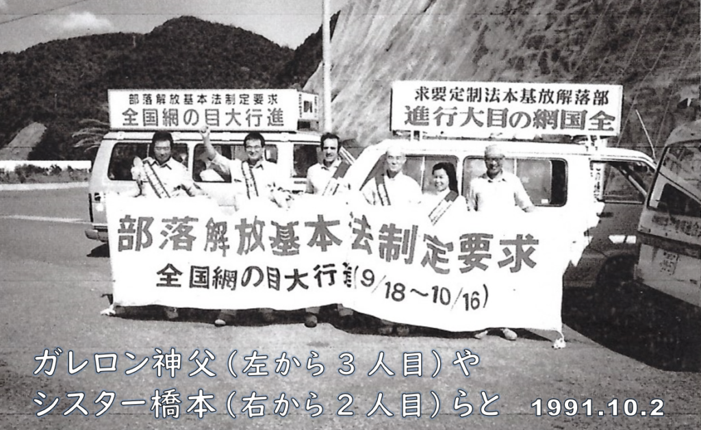 「部落解放基本法制定要求」の横断幕を持つ人たち。1991年10月2日。ガレロン神父（左から3番目）やシスター橋本（右から2番目）らと。