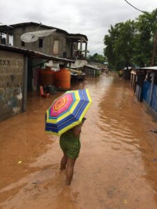 雨で浸水した町を傘をさして歩く人物